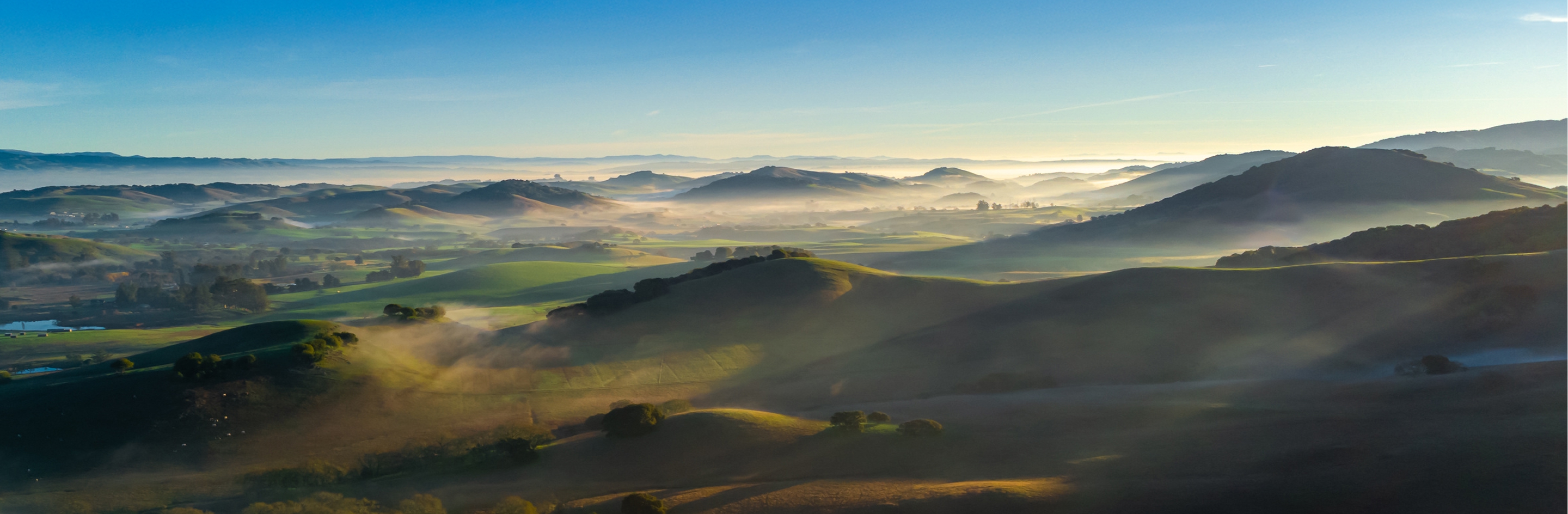 Rolling hills and valleys at sunrise with morning mist